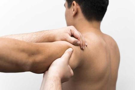Un kinésitérapeute manipule l'épaule de son patient