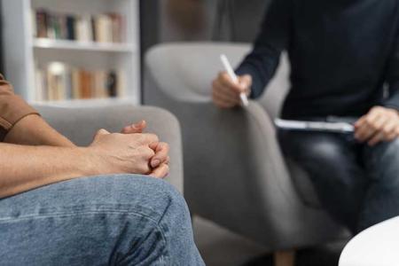 Un psychologue à l'écoute de son patient prend des notes.