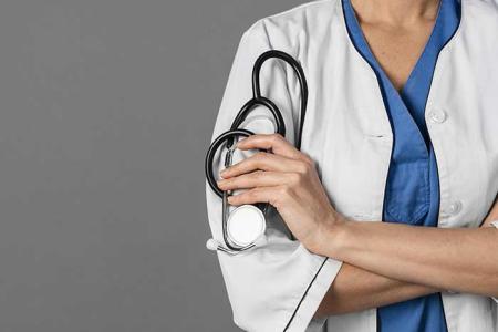 Un medecin de face, les bras croisés tient son stéthoscope dans sa main.